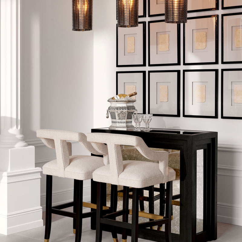 The Bar Metropolitan styled in an elegant room with cream bar stools, a silver champagne bucket, and gallery wall — part of The Met x Eichholtz collection