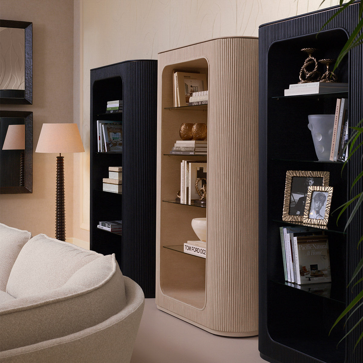 Two Bogota display cabinets in charcoal oak veneer styled in a luxury living room with books, brass accessories, a floor lamp, and a curved white sofa
