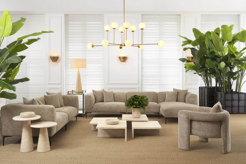 A curated Eichholtz living room — neutral tones with globe chandelier, cream sectional, and tropical plants