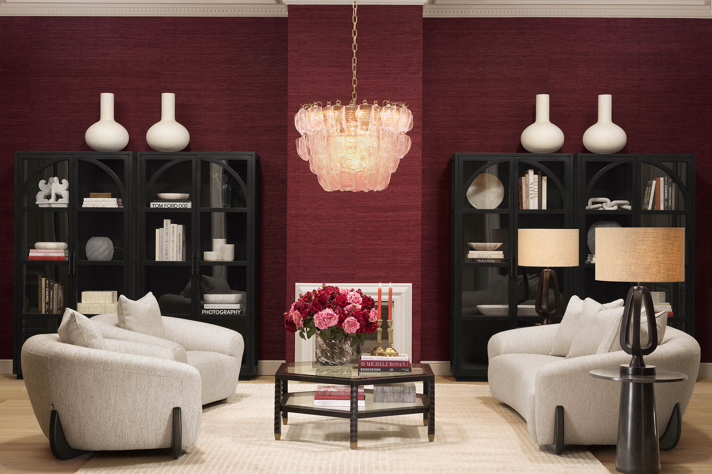 A curated Eichholtz room featuring symmetric black display cabinets flanking a statement chandelier in a bold red-toned living room.