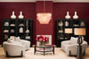 A curated Eichholtz room featuring symmetric black display cabinets flanking a statement chandelier in a bold red-toned living room.