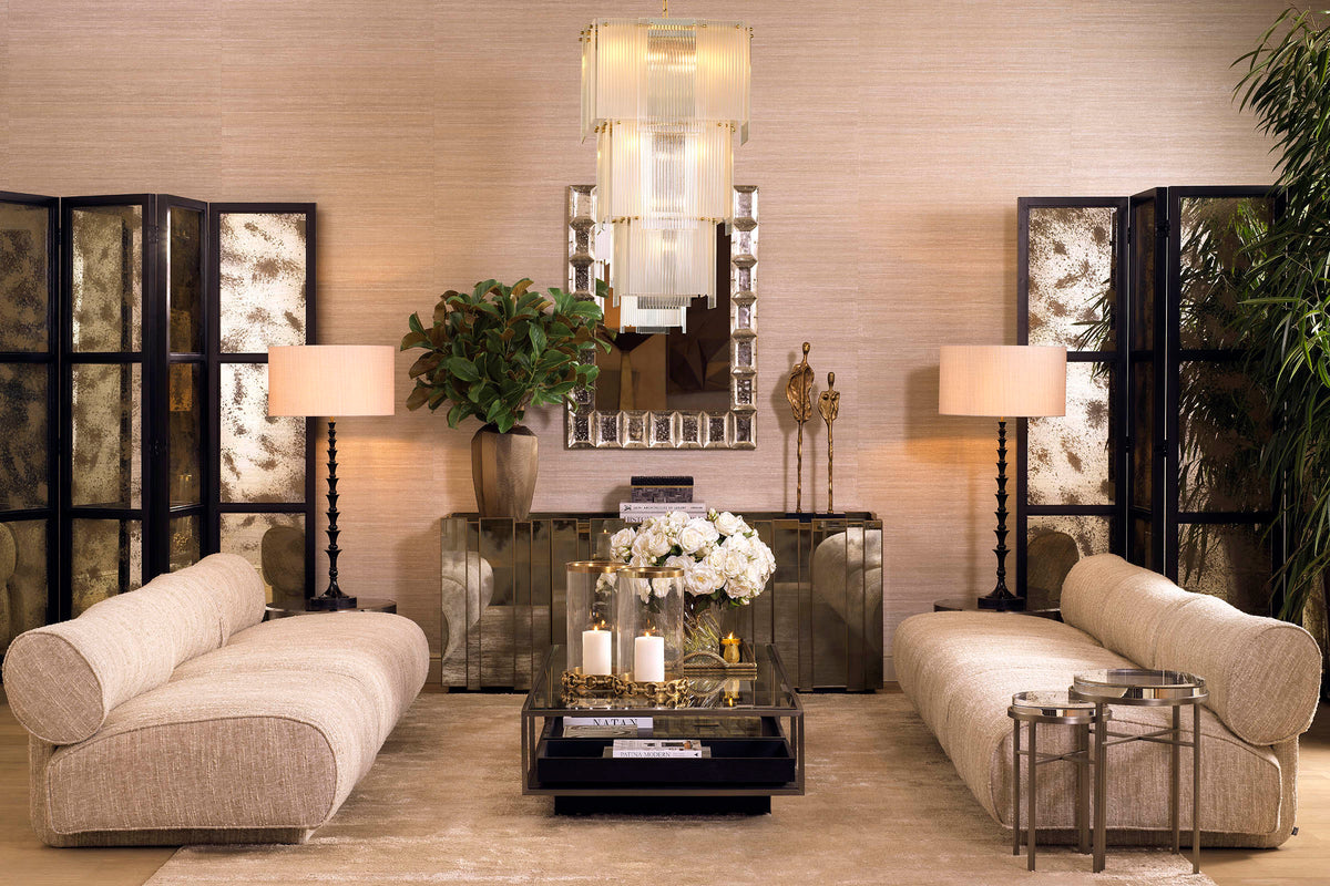 A curated Eichholtz living-room vignette — cream boucle seating, symmetric mirrored consoles, layered brass accents — the kind of welcome the Tivoli Village showroom is built for.