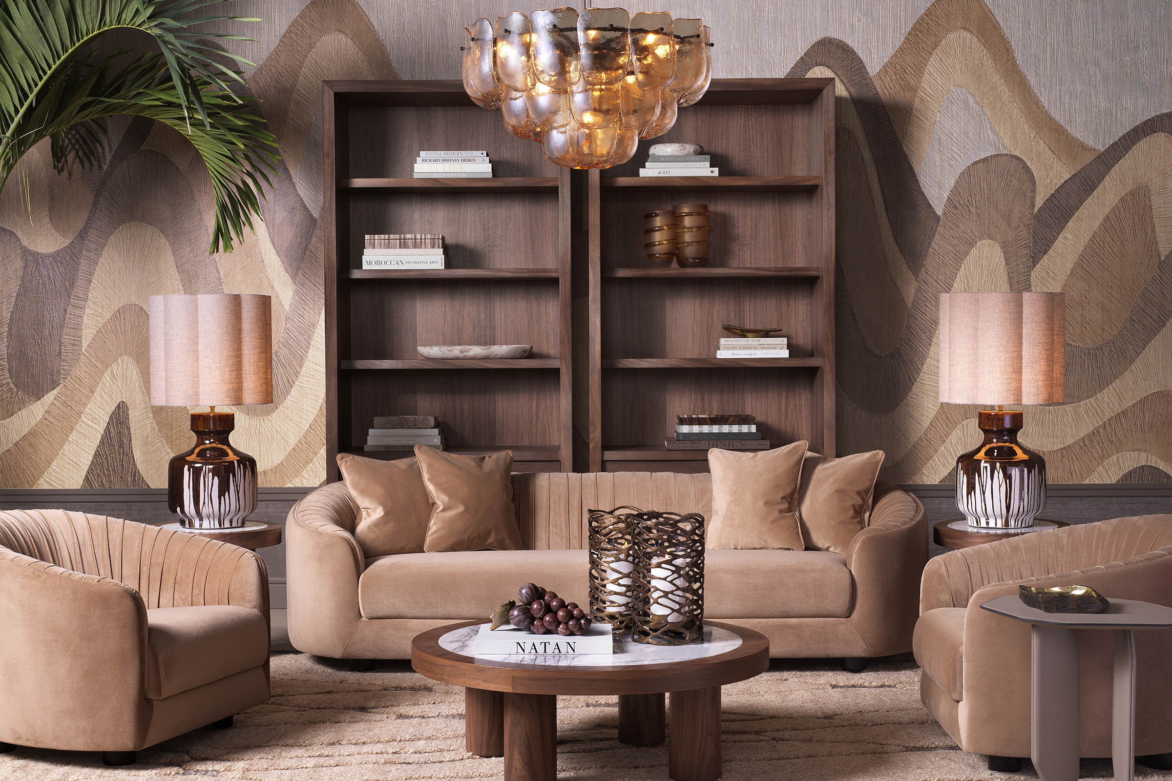 An Eichholtz living room with a tan velvet sofa, walnut bookcases, and a low round coffee table — a textbook example of round-table geometry anchoring a compact seating arrangement.