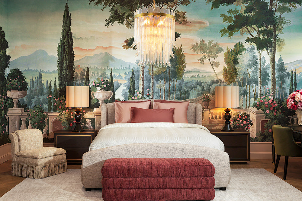 An Eichholtz bedroom vignette — upholstered bed with Tuscan mural backdrop and crystal chandelier overhead