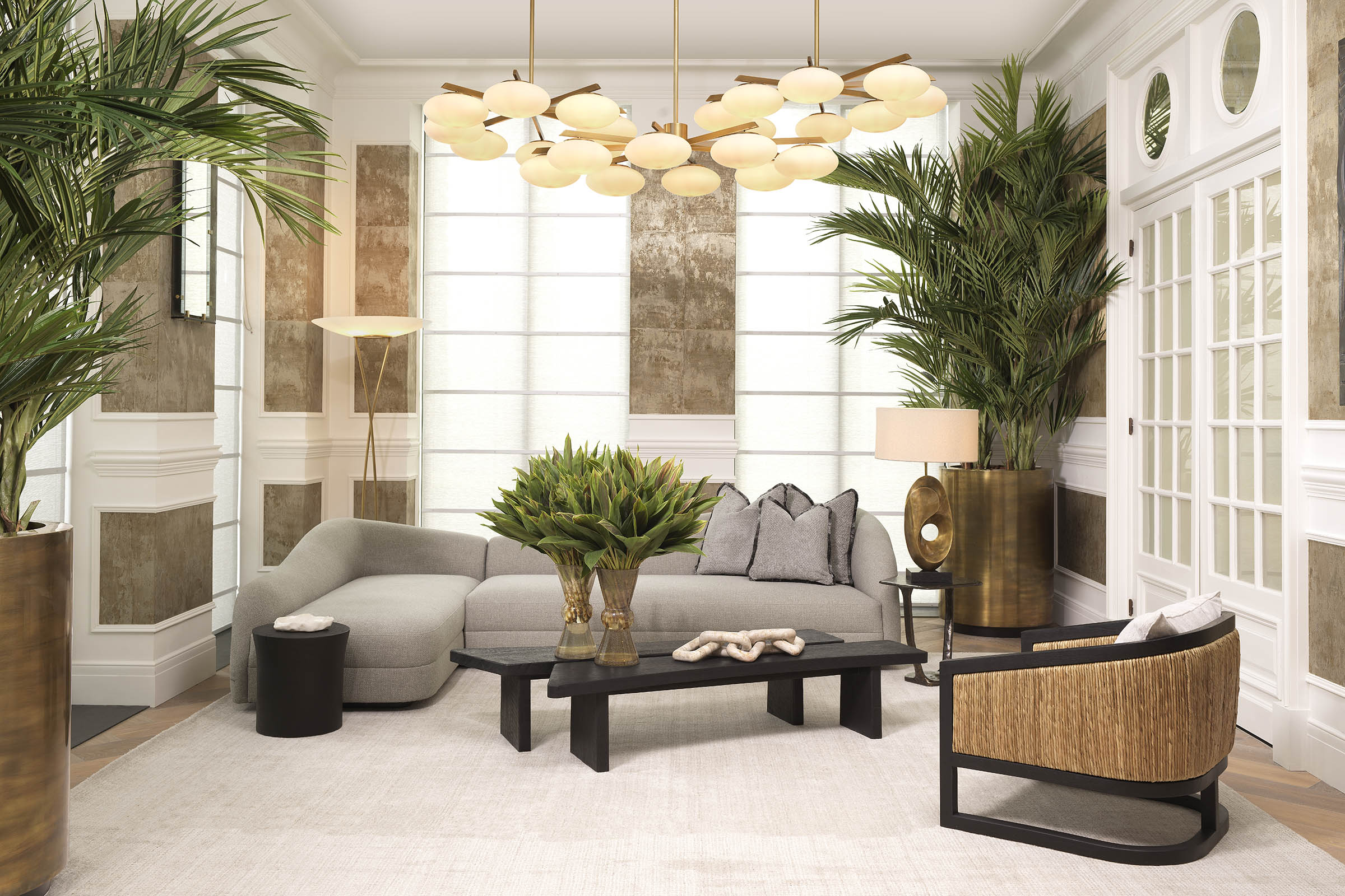 A layered Eichholtz living-room vignette with a statement chandelier anchoring the seating group.