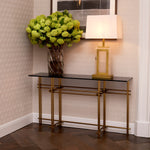 Eichholtz Console Table Quinn brass tones characterise the sturdy base formed by an intriguing interplay of bars. With a