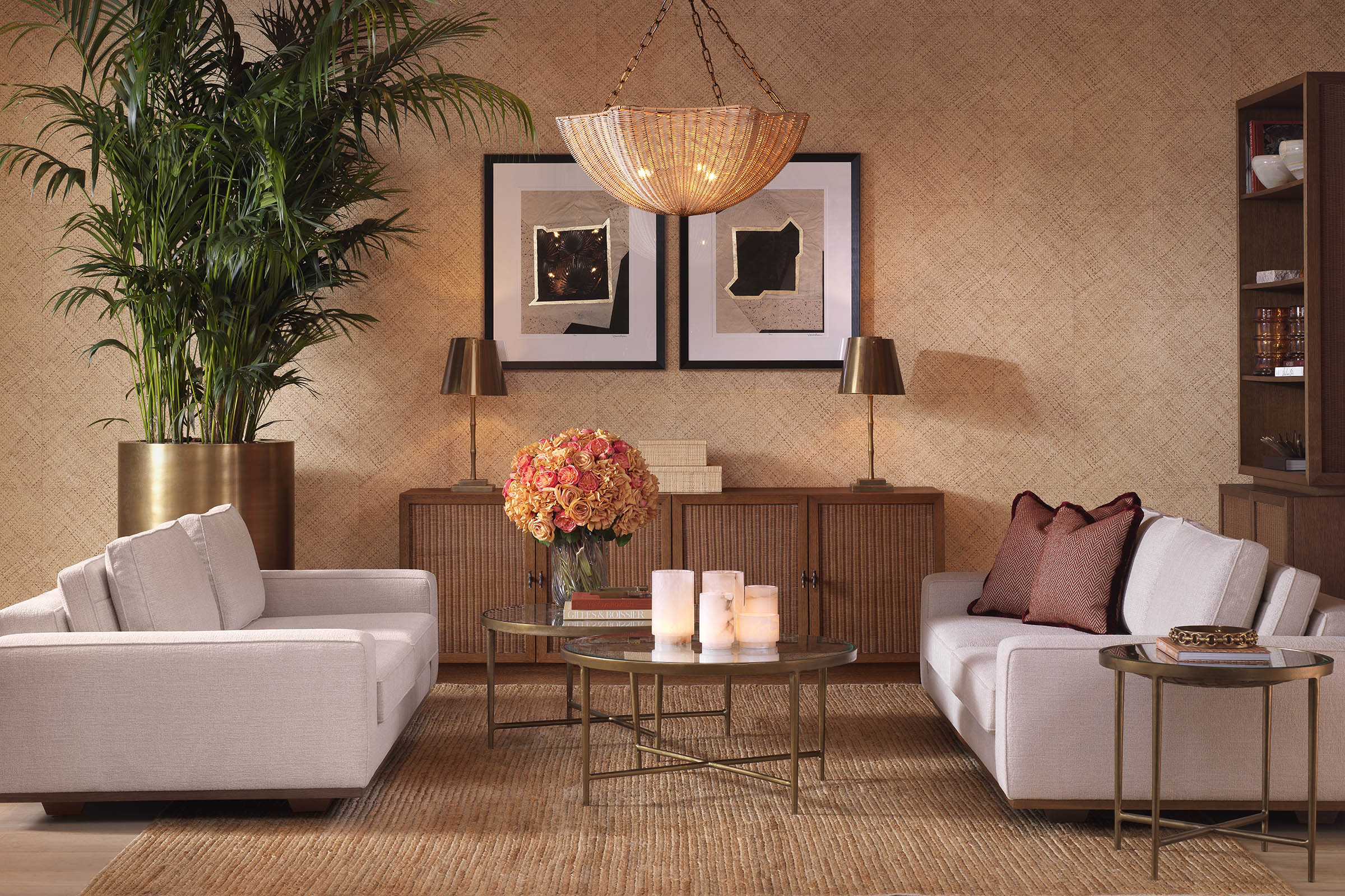 A warm Eichholtz living room — rattan sideboard styled with brass lamps, wall art, and cream sofas