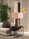 Decorative table lamp with textured base placed on black nesting side tables beside a neutral sofa in an elegant living room.