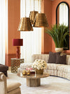 Curved sofa arrangement with stone coffee table, brass pendant lights, floral centerpiece, and warm terracotta walls in a refined living room.